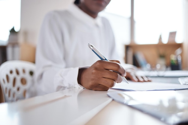 Photo d'une femme d'affaires méconnaissable remplissant des papiers à son bureau dans un bureau moderne