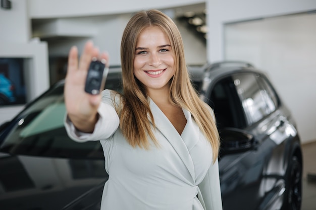 Photo d'une femme d'affaires séduisante et jeune dans une salle d'exposition de voitures femme tenant les clés de sa nouvelle voiture