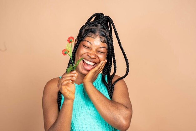 Photo d'une femme africaine agréable et optimiste tenant des fleurs et se sentant dans un espace vide.