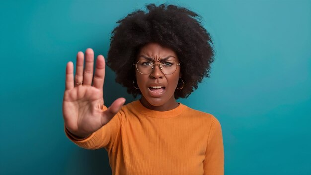 Photo d'une femme afro-américaine qui s'arrête, fait un geste, a une expression faciale en colère, exige d'arrêter de parler.