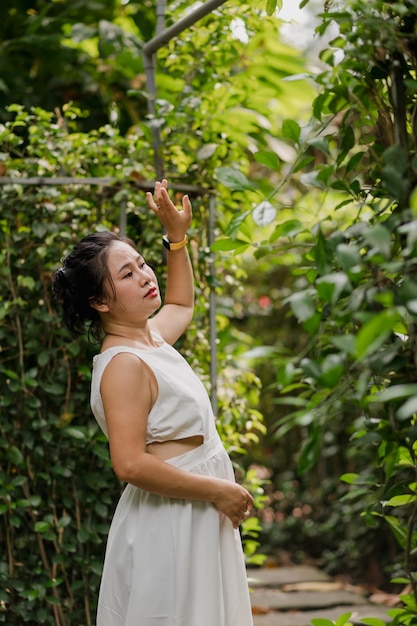 Photo d'une femme asiatique en robe blanche marchant dans le parc en plein air