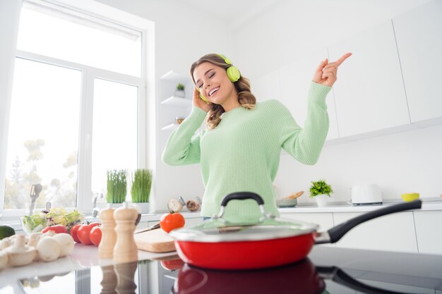 Photo d'une femme au foyer joyeuse qui écoute des écouteurs