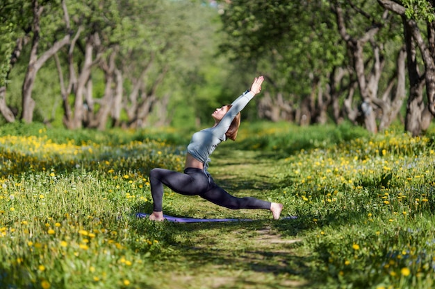 Photo de femme avec les bras levés pratiquant le yoga dans les bois