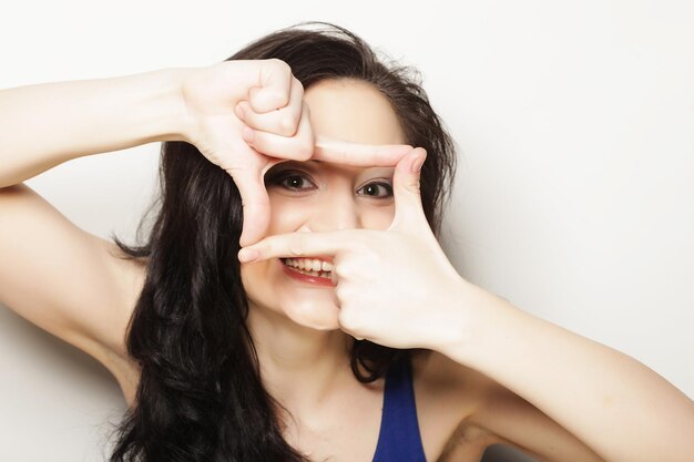 Photo d'une femme brune créant un cadre avec des doigts ou des boutons-pression