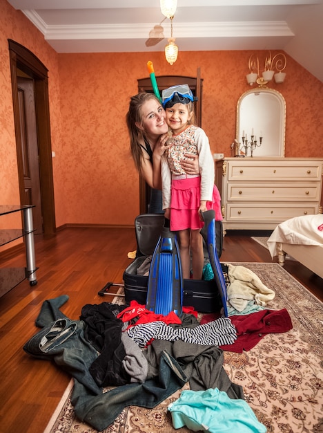 Photo de femme étreignant une petite fille en masque et tuba debout dans une valise