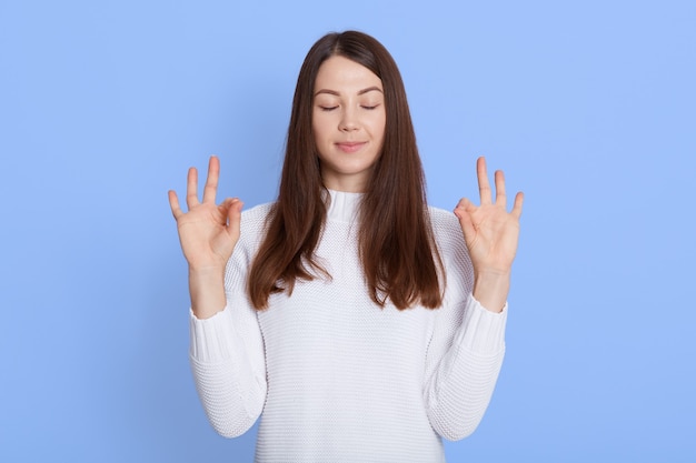 Photo de femme européenne détendue montre signe zen ou ok