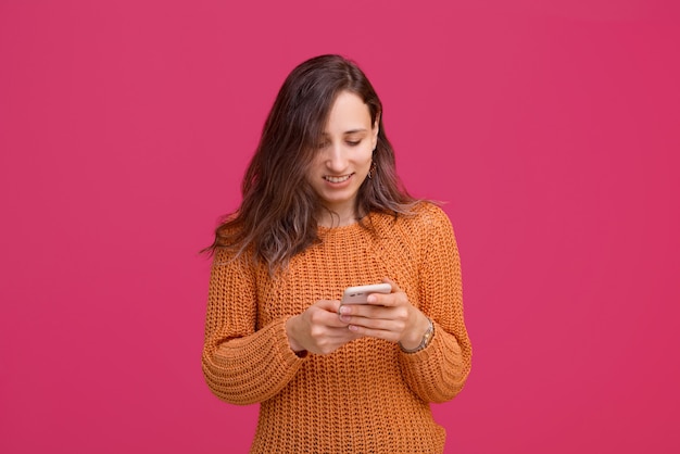 Photo de femme heureuse à l'aide de smartphone et portant un pull jaune