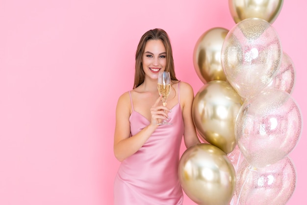 La photo d'une femme heureuse lève une coupe de champagne et de nombreuses montgolfières sont venues célébrer la fête