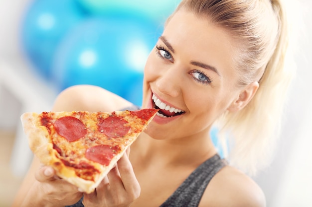 Photo d'une femme heureuse mangeant une pizza dans un club de santé