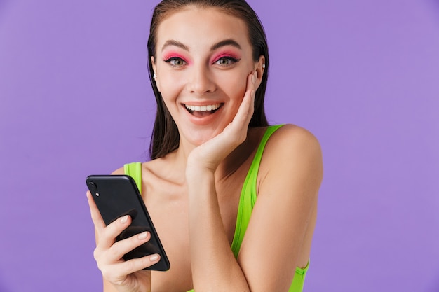 Photo de femme heureuse de mode avec le maquillage lumineux tenant le smartphone et souriant