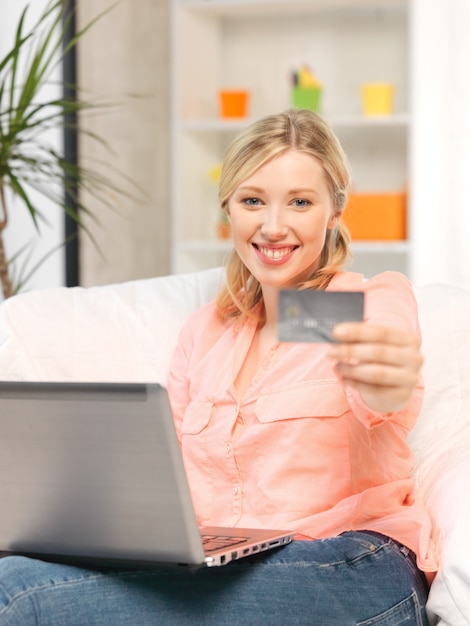 photo d'une femme heureuse avec un ordinateur portable et une carte de crédit.