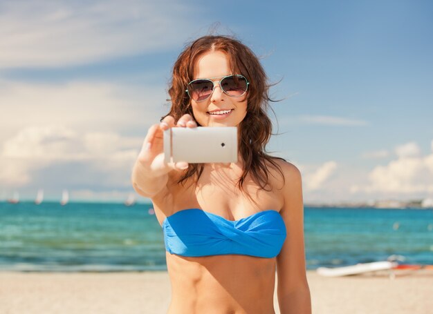 photo d'une femme heureuse avec un téléphone sur la plage.