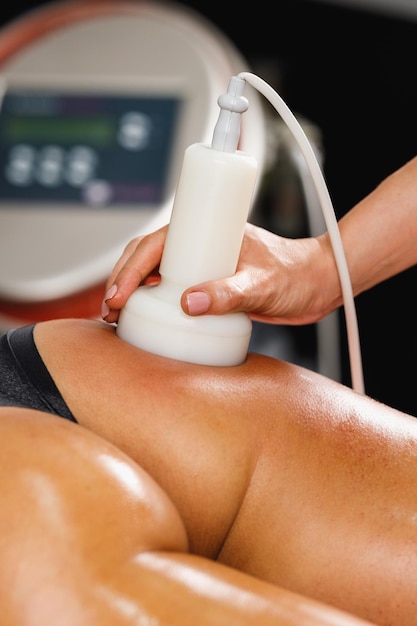 Photo d'une femme méconnaissable recevant un massage anti-cellulite au salon de beauté. Elle a un traitement de cavitation par ultrasons pour réduire la graisse.