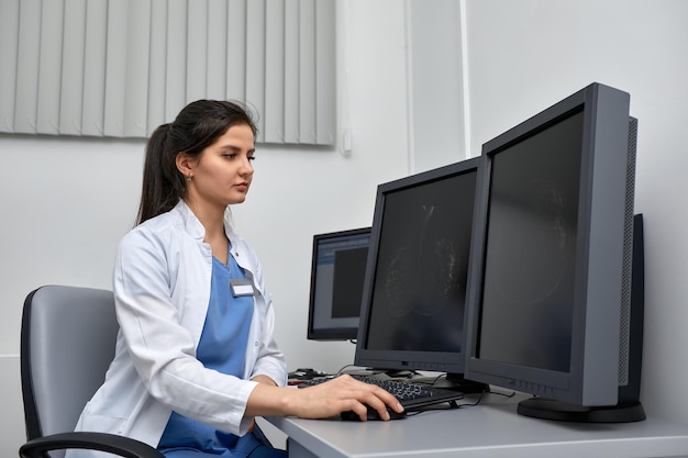 Photo d'une femme médecin travaillant sur une expertise médicale alors qu'elle était assise à son bureau devant un ordinateur portable