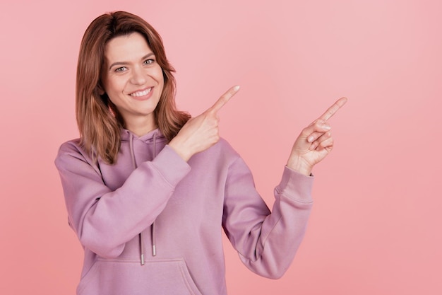 Photo d'une femme mûre attirante indiquer les doigts espace vide ad promo recommander isolé sur fond de couleur rose