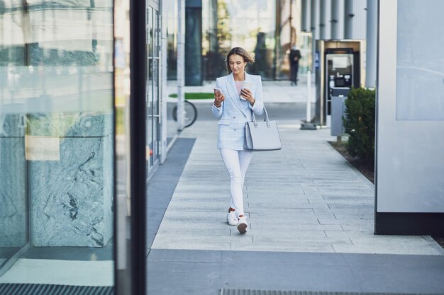 Photo d'une femme séduisante adulte avec un smartphone marchant dans la ville