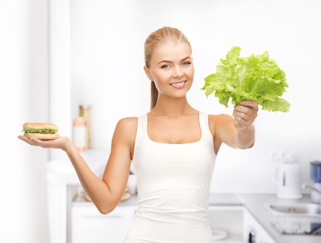 photo de femme sportive avec des feuilles vertes et un hamburger