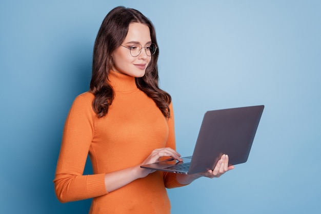 Photo d'une femme de travail confiante tenir un écran d'ordinateur portable en tapant posant sur fond bleu