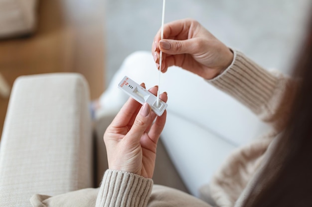 Photo d'une femme utilisant un coton-tige lors d'un test PCR de coronavirus Une femme prélève un échantillon de coronavirus de son nez à la maison une femme à la maison utilisant un écouvillon nasal pour COVID19