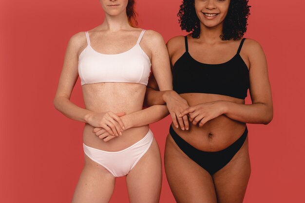 Photo de femmes multiraciales naturelles, corps positif. Femmes féministes, isolées sur fond rose. Concept beauté naturelle et pouvoir des filles.