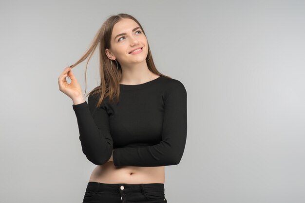 Photo d&#39;une fille blonde souriante rêveuse qui pose en haut noir. - image