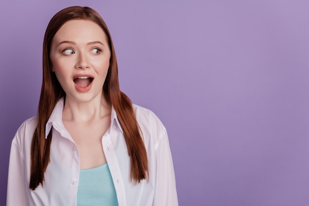 La photo d'une fille étonnée montre une expression d'émotion omg regarde un espace vide isolé sur fond violet