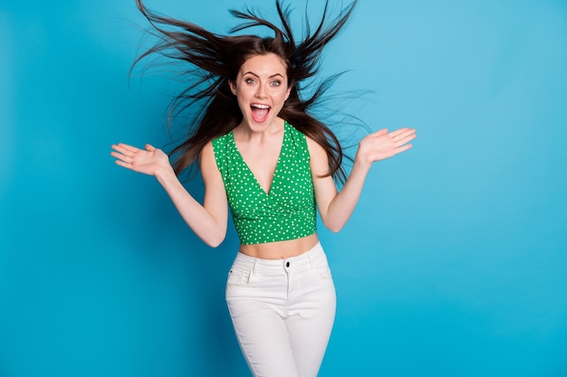 Photo d'une fille folle profitez de se réjouir de l'air du vent lancer une coupe de cheveux porter un pantalon singulet isolé sur fond de couleur bleu