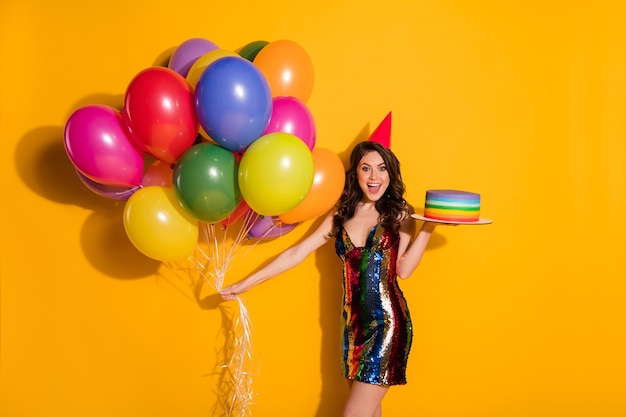 Photo d'une fille joyeuse et positive profitez d'une occasion festive de fêter des ballons de gâteau porter un cône d'anniversaire de mini jupe courte isolé sur un fond de couleur brillante et brillante