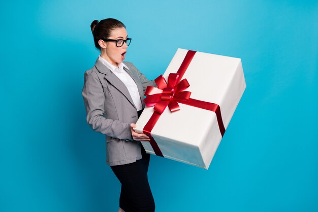 Photo d'une fille patronne étonnée obtenir un énorme cadeau porter des blazers gris jupe fond bleu isolé