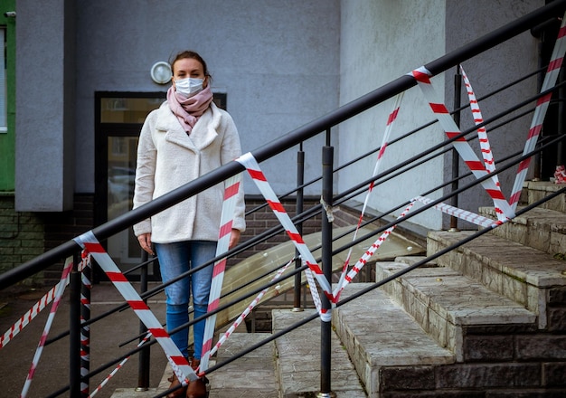 Photo d'une fille portant un masque debout dans la rue avec des bandes d'avertissement de danger