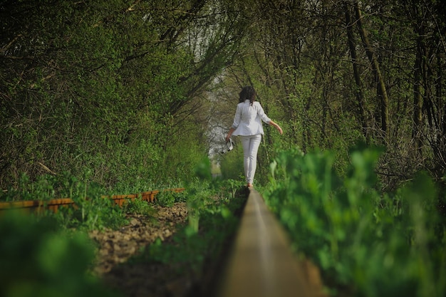 Photo d'une fille qui s'enfuit sur les rails dans la nature