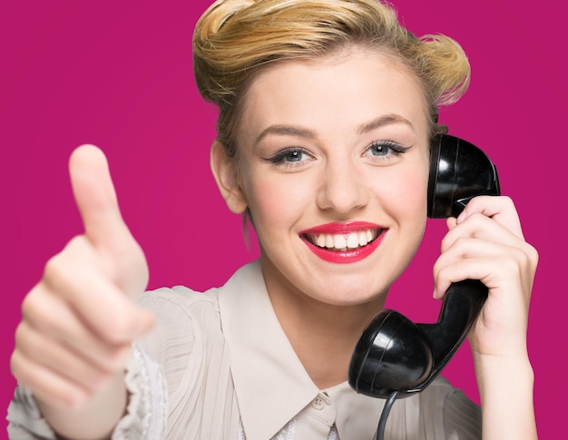 Une photo de la fille souriante avec un téléphone vintage.