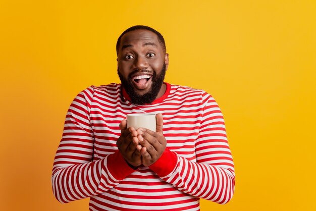 Photo de fou excité tenir la tasse bouche ouverte sur fond jaune