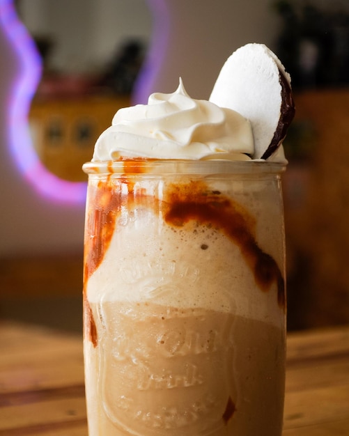 Photo photo frappe de caramelo servido en un vaso transparent sur un fondo de madère