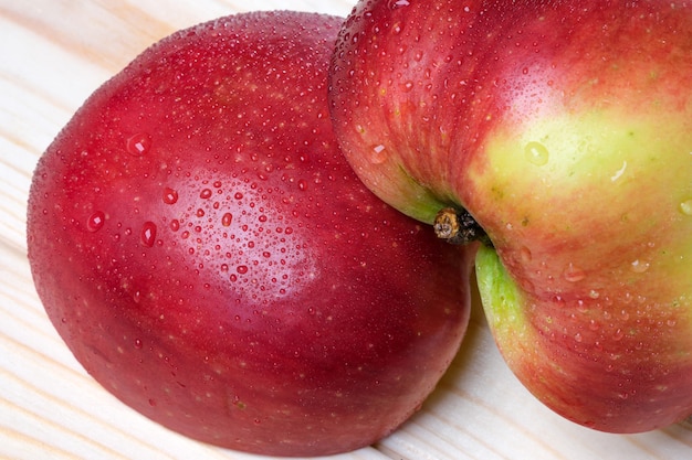 Photo de fruits rouge pomme coupée sucrée mûre avec des gouttes de rosée sur un fond en bois clair close-up macrophotographie