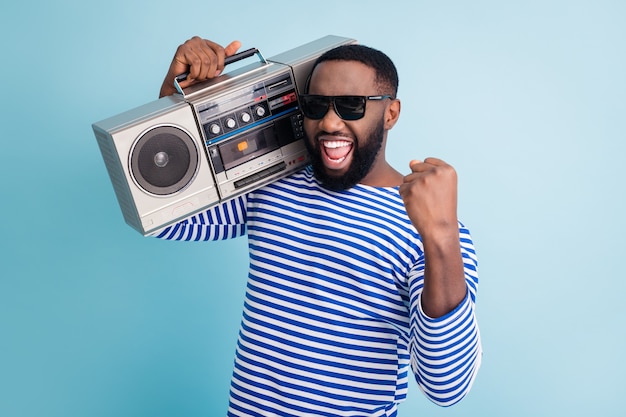 Photo de funny guy tenir un magnétophone rétro sur l'épaule lever le poing