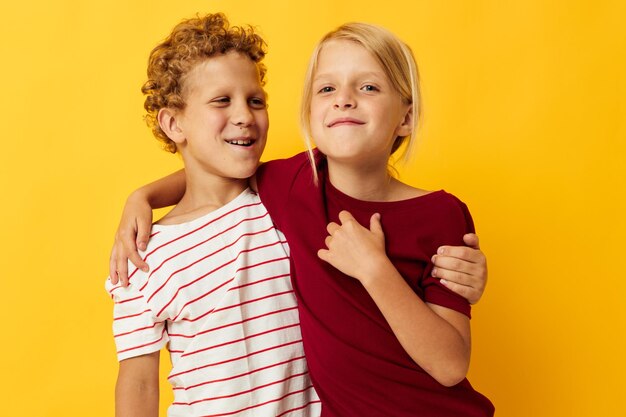 Photo d'un garçon et d'une fille positifs debout côte à côte posant des émotions d'enfance sur fond jaune