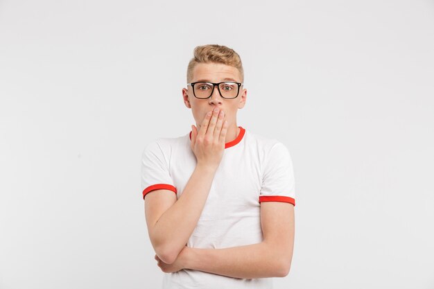 Photo d'un gars effrayé à lunettes vous regardant et couvrant la bouche dans la peur ou le choc isolé sur blanc