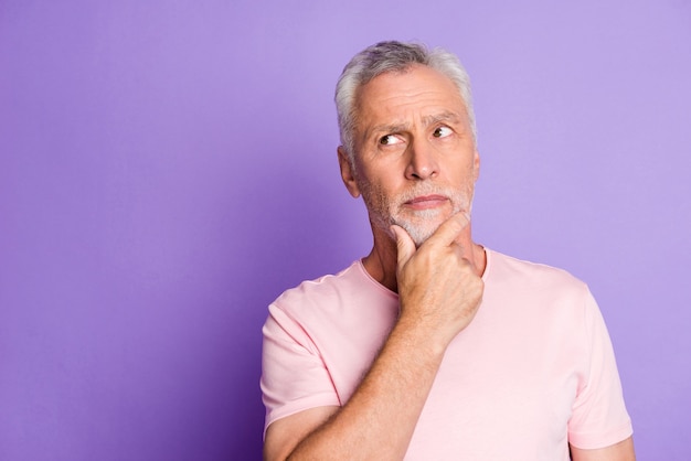 Photo de grand-père à la retraite bras menton regard pensif espace vide porter un t-shirt rose fond de couleur violet isolé