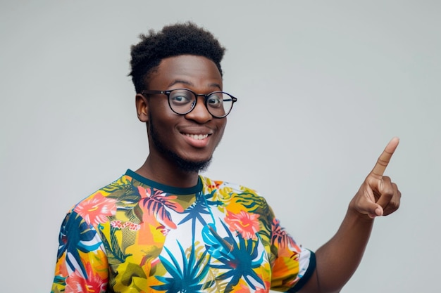 Photo une photo gratuite en intérieur d'une personne positive en t-shirt rouge décontracté avec l'index à côté