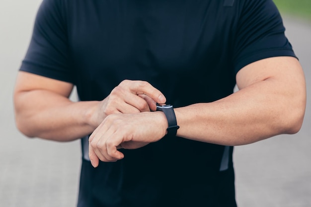 Photo en gros plan d'un athlète masculin choisissant un programme sportif sur un bracelet de remise en forme