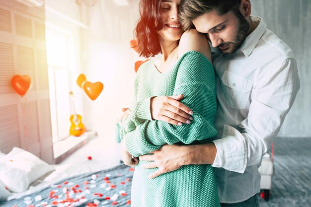 La photo en gros plan d'un beau jeune homme embrasse sa jolie femme bien-aimée lors d'une journée romantique