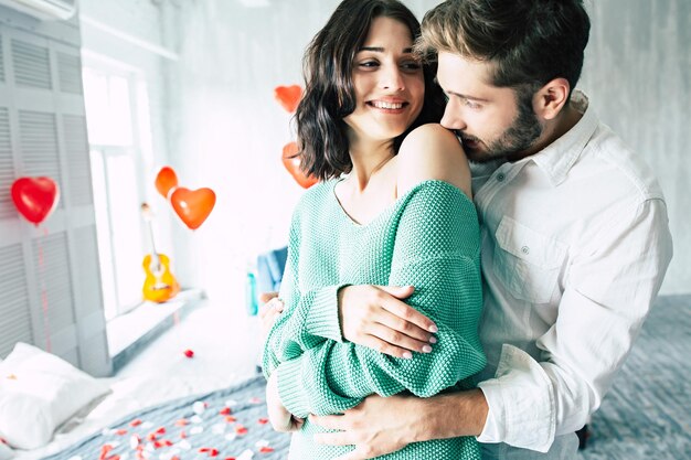 La photo en gros plan d'un beau jeune homme embrasse sa jolie femme bien-aimée lors d'une journée romantique