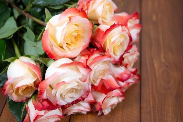 Photo gros plan d'un bouquet de roses beiges et rouges sur un fond de bois foncé