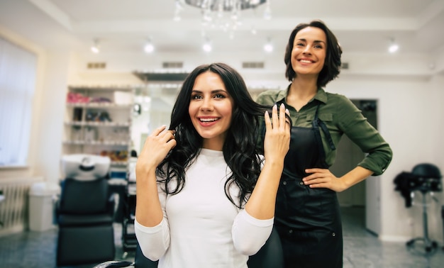 Photo en gros plan d'une coiffeuse, qui touche les cheveux de son client heureux, tout en faisant une nouvelle coiffure.