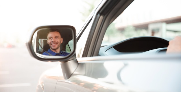 La photo en gros plan du jeune bel homme réussi conduit sa voiture moderne