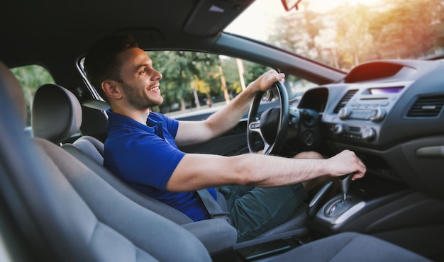 La photo en gros plan du jeune bel homme réussi conduit sa voiture moderne