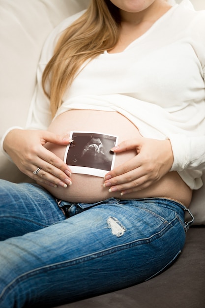 Photo gros plan d'une femme enceinte posant avec une image de résidence à ultrasons