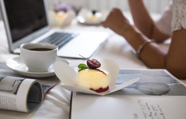 photo en gros plan de femmes sur un grand lit blanc à la maison avec un ordinateur portable en tasse et une délicieuse pâtisserie sur une assiette