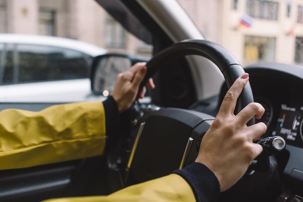 Photo en gros plan d'une fille méconnaissable qui conduit une voiture à deux mains Mise au point sélective sur le bras droit